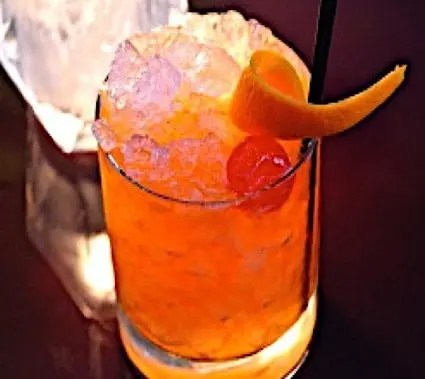 Cocktail Buffalo Bill, boisson orange dans un verre, décoré d'un zeste en spirale