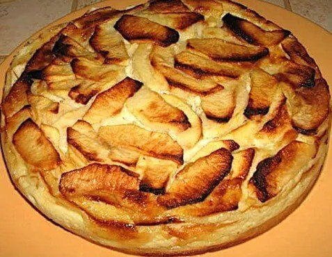 Flognarde aux pommes dorée et gonflée dans son moule, saupoudrée de sucre