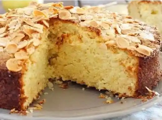 Gâteau 5 minutes aux amandes couvert d'amandes effilées, part coupée sur une assiette