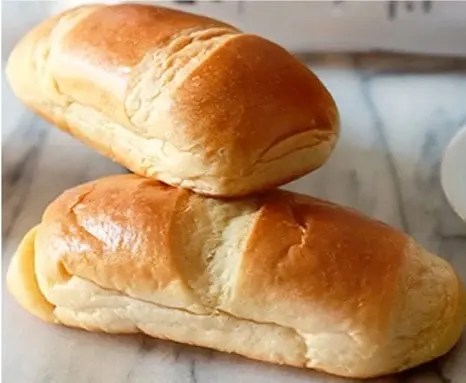 Pain au lait maison doré en forme de navette, incisé et parsemé de sucre perlé