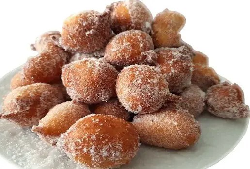 Croustillons dorés saupoudrés de sucre glace, servis chauds en cornet