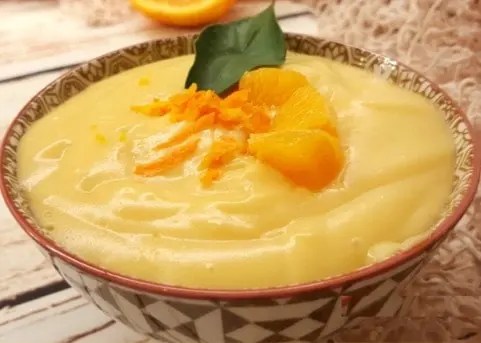 Crème pâtissière à l'orange lisse dans un bol, avec zeste d'orange