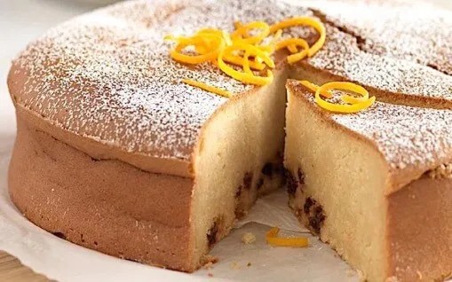 Gâteau aux haricots blancs saupoudré de sucre glace, part découpée montrant la mie moelleuse et les raisins sultanines