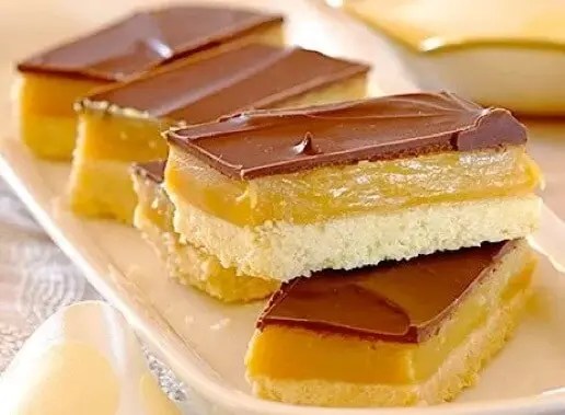Sablés du millionnaire coupés en carrés, montrant les couches de sablé, de caramel et de chocolat