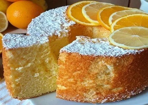 Gâteau nuage au citron et à l’orange démoulé, saupoudré de sucre glace et décoré d’agrumes confits