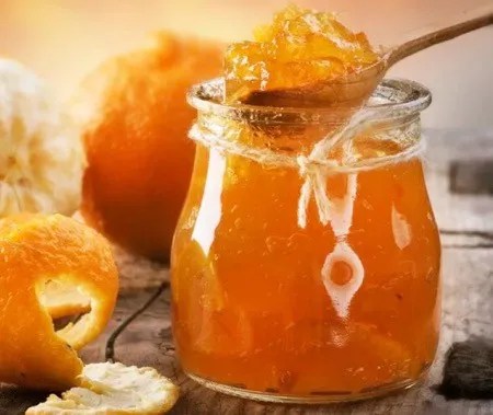 Confiture d'orange maison en pot avec fines lanières de zestes, oranges coupées en rondelles