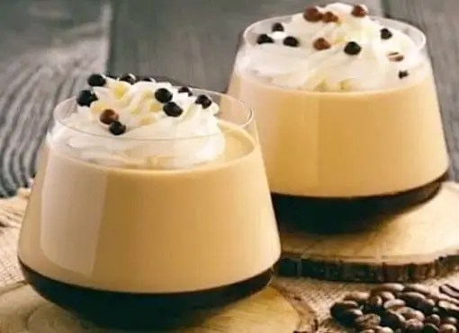Panna cotta au café en tasse à expresso, décorée de crème et billes de chocolat