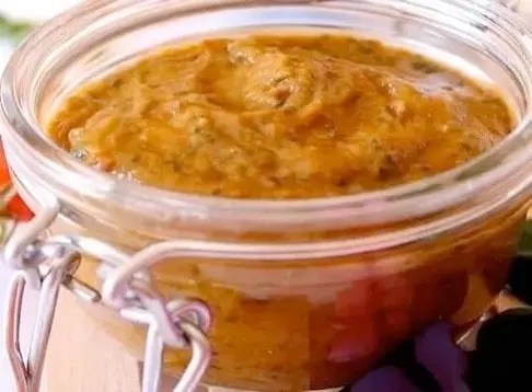 Pesto aux aubergines et tomates cerises dans un bocal, feuilles de basilic