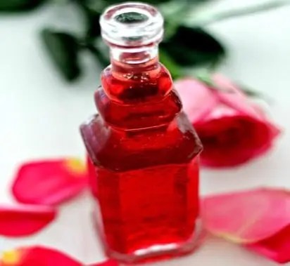 Sirop de rose maison rose vif dans une bouteille en verre, avec des pétales