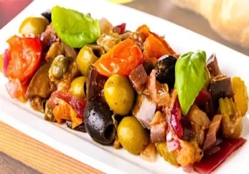 Caponata de légumes au pesto de basilic servie froide dans un plat, avec du pain grillé