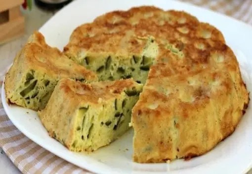 Gâteau omelette de courgettes au four coupée en parts, dorée au parmesan et parsemée de rondelles de courgette