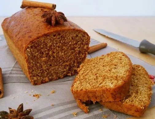 Pain d'épices de Dijon en tranches fines sur une planche, mie claire et serrée piquée de graines d'anis vert
