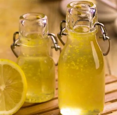 Sirop de citron grand-mère jaune dans une bouteille, avec des citrons frais