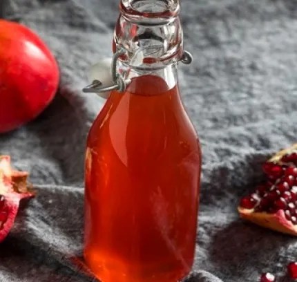 Grenadine maison rouge dans une bouteille, avec des grenades ouvertes