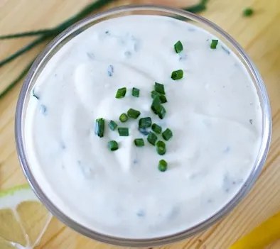 Sauce légère au yaourt aux herbes fraîches dans un bol, avec une salade