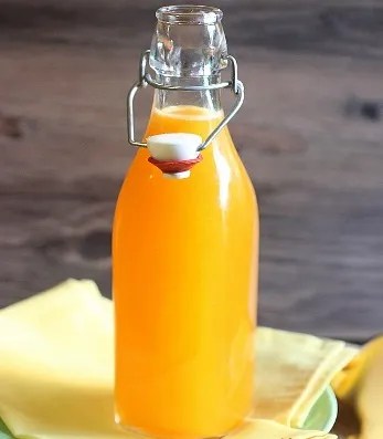 Sirop d'orange maison orangé dans une bouteille, avec des oranges fraîches