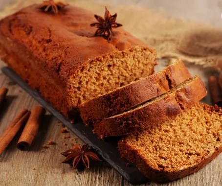 Pain d'épices alsacien moelleux tranché sur une planche, avec bâtons de cannelle et étoiles d'anis