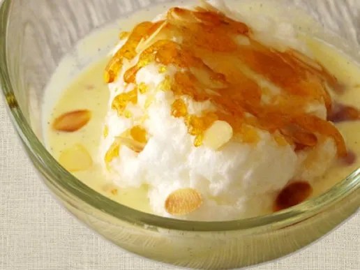 Île flottante démoulée sur crème anglaise, nappée de caramel et parsemée d'amandes effilées grillées