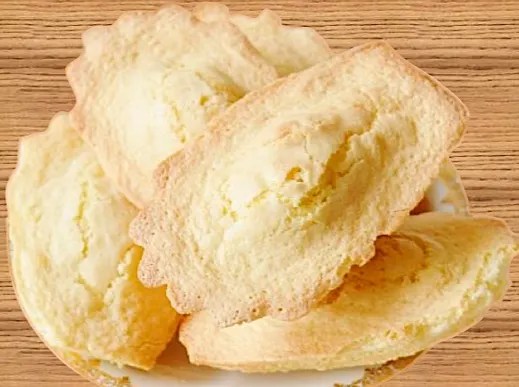 Madeleines landaises croustillantes dehors et moelleuses dedans, rangées dans une boîte métallique