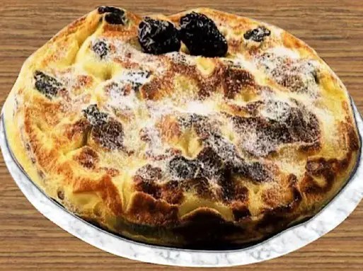 Pachade aux pruneaux dorée cuite au four, part coupée montrant les pruneaux dans la pâte