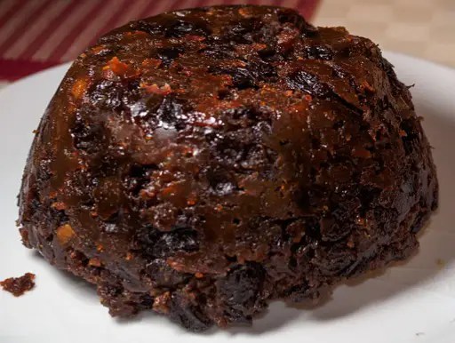 Plum-pudding du Nord démoulé et flambé au rhum, saupoudré de sucre, avec sa sauce au beurre et au rhum