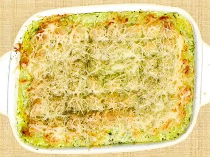 Gratin de ravioles aux courgettes servi dans un plat en terre, dessus doré au comté