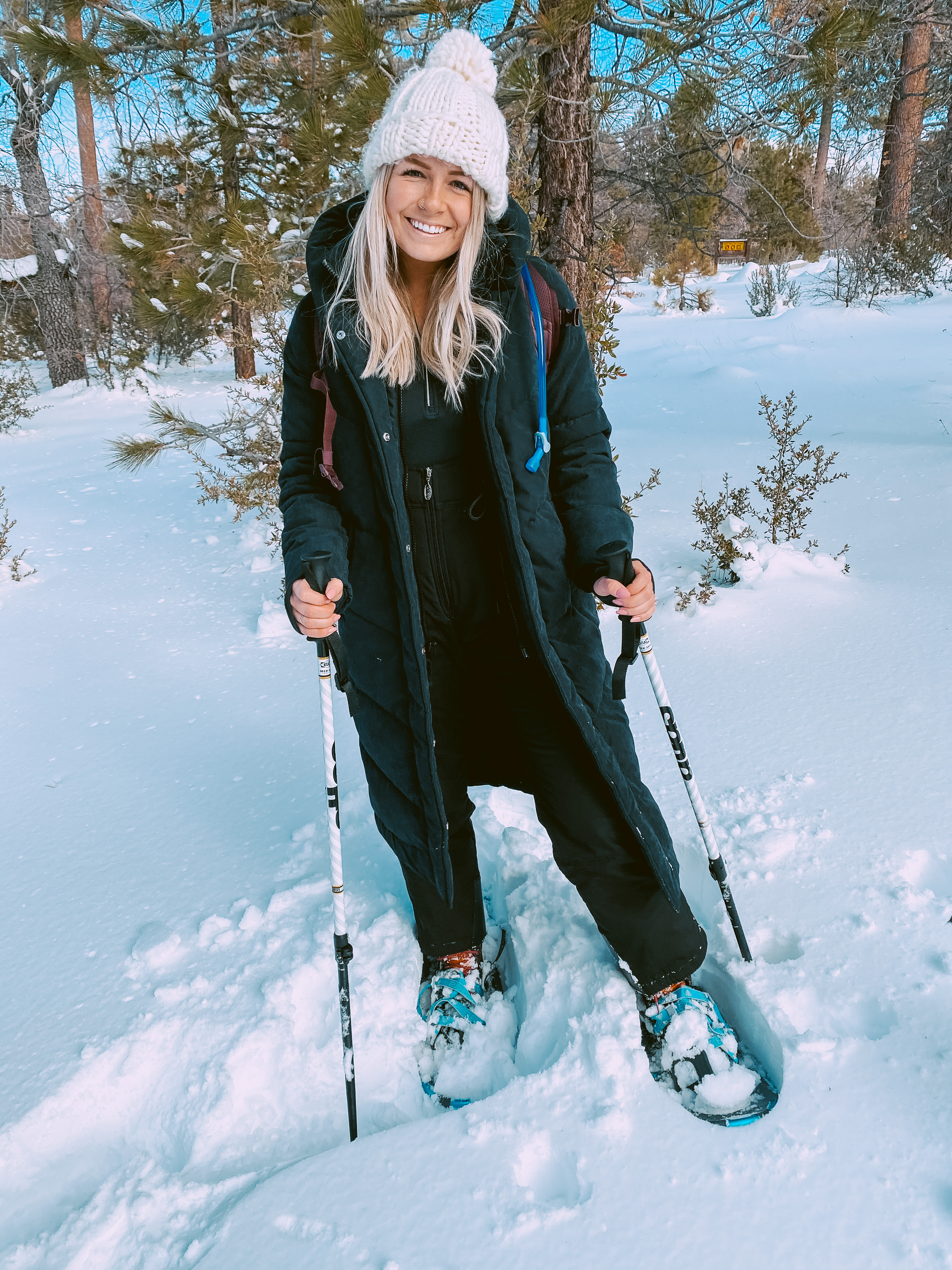 Ariana wearing the Ultra Long Puffer standing in the snow wearing snow shoes