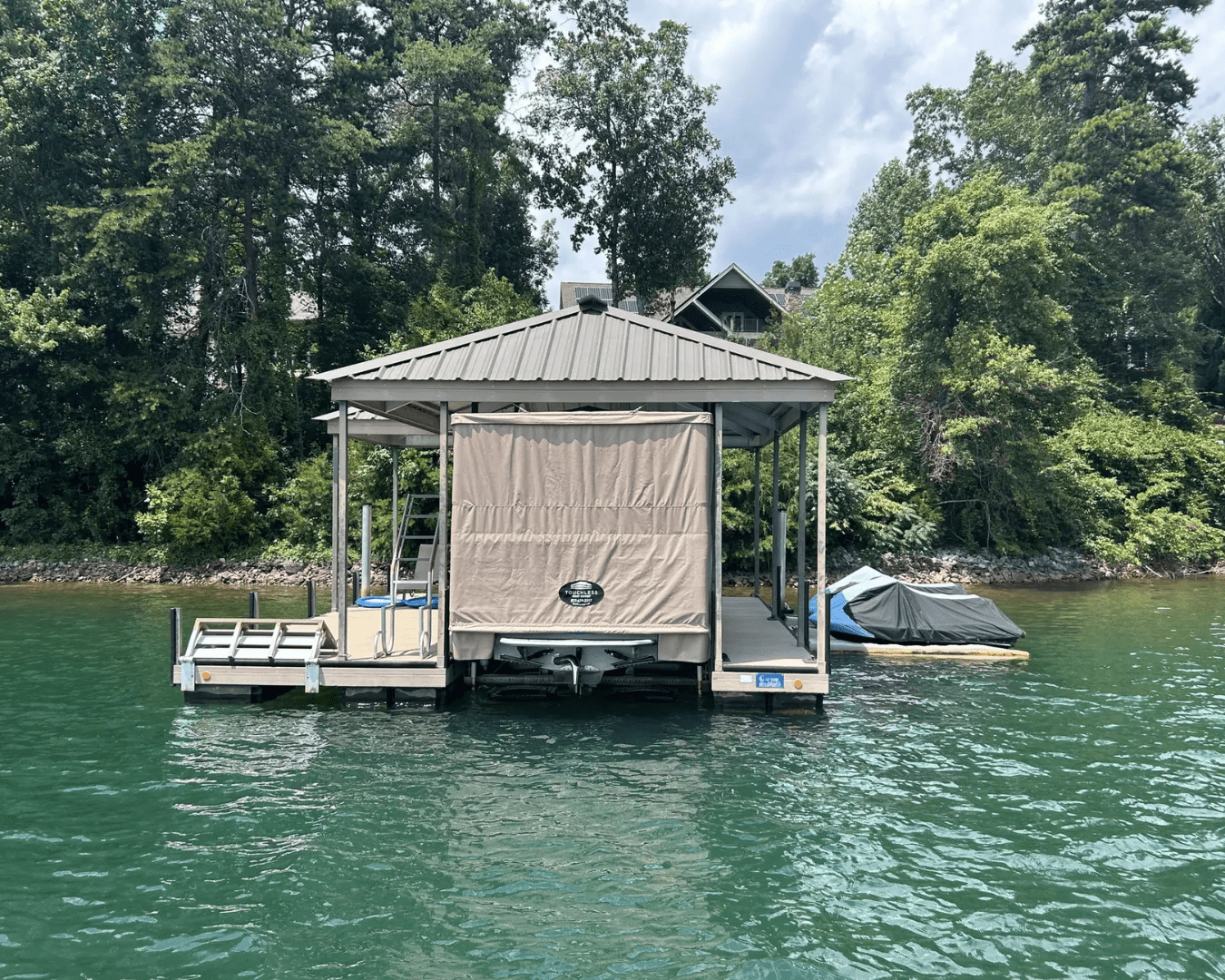 Beautiful, residential dock made by Custom Dock Systems, with Touchless Boat Cover covering large pontoon boat.
