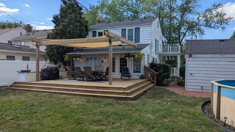 Custom-built backyard deck with a cedar pergola and shade sail