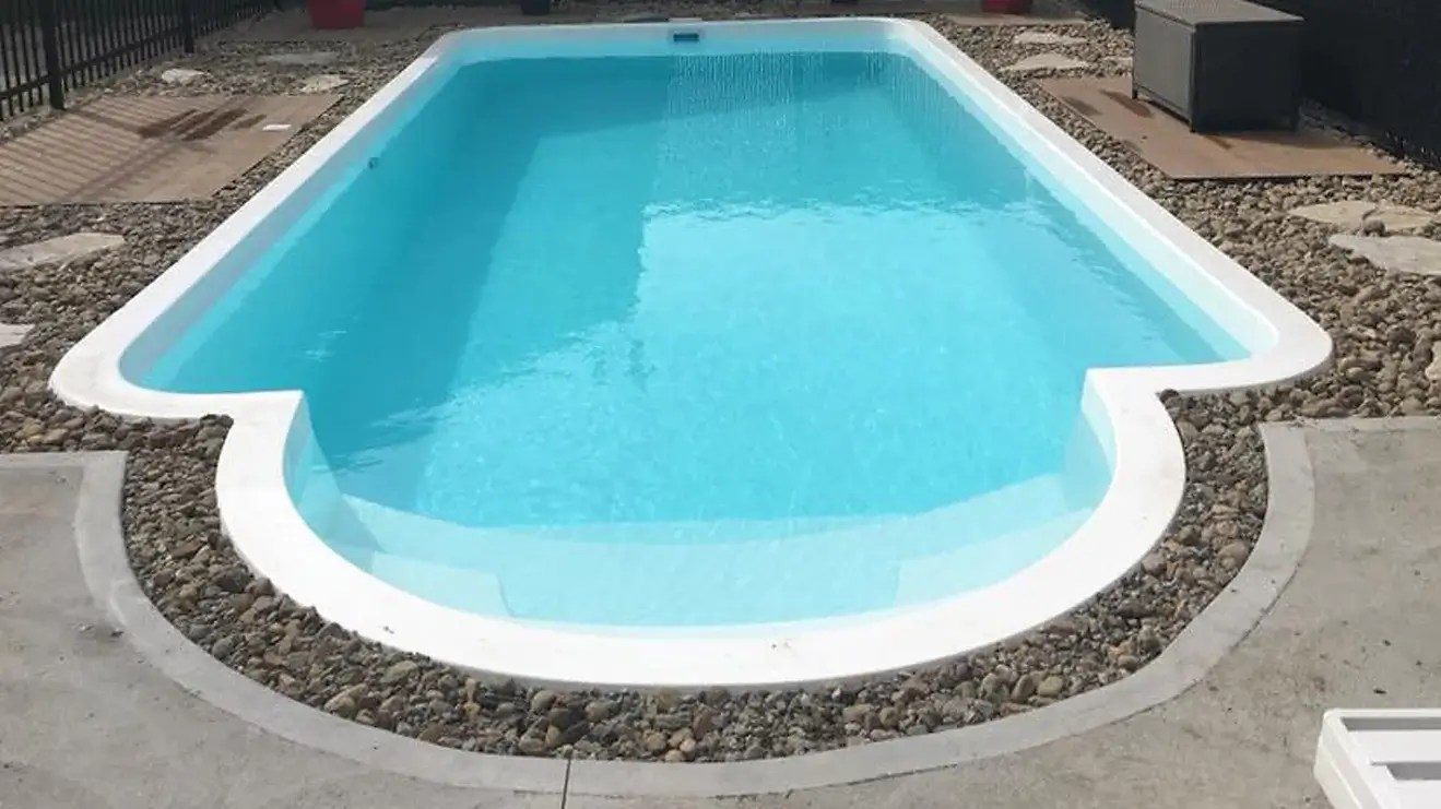 In-ground swimming pool with clear blue water, surrounded by stone landscaping and a concrete deck, ideal for outdoor relaxation and recreation.