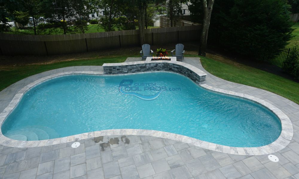 freeform gunite inground pool with fire pit sitting area and retaining wall