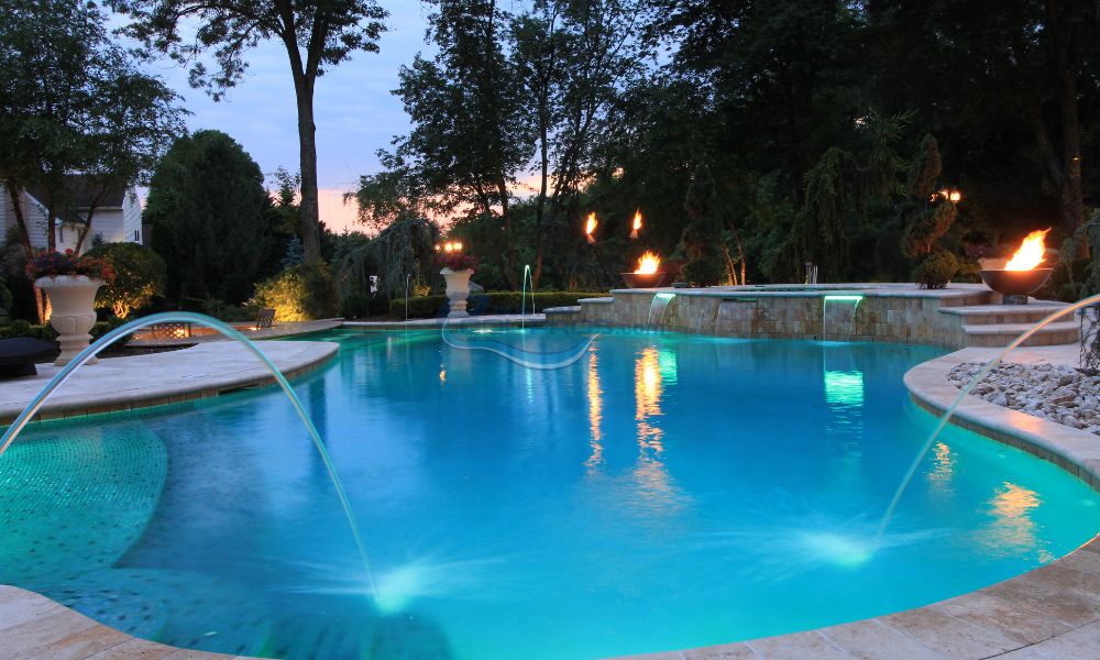 water jets and fire pits at night in inground gunite swimming pool