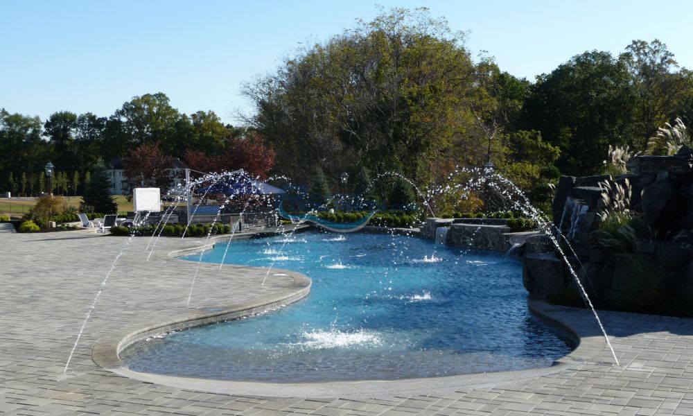 freeform gunite inground pool with water jets spraying into water