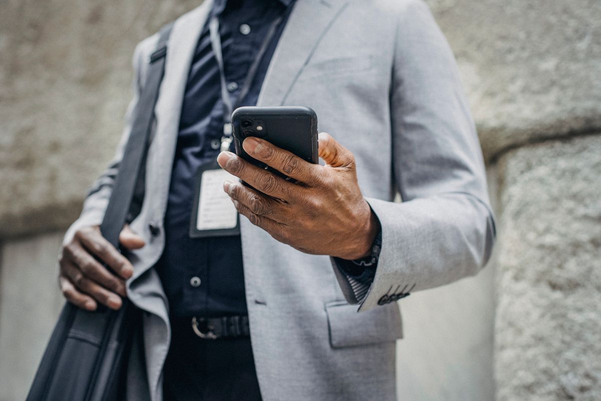 Businessman checking his phone while carrying a bag on the street