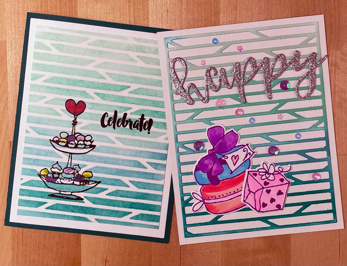 Two greeting cards on a wooden surface. The left card, crafted with stencils, features cupcakes and the word "Celebrate." The right card boasts gifts, bows, hearts, sequins, and the word "happy" in glittery letters—an inspiring display of the art of cardmaking.