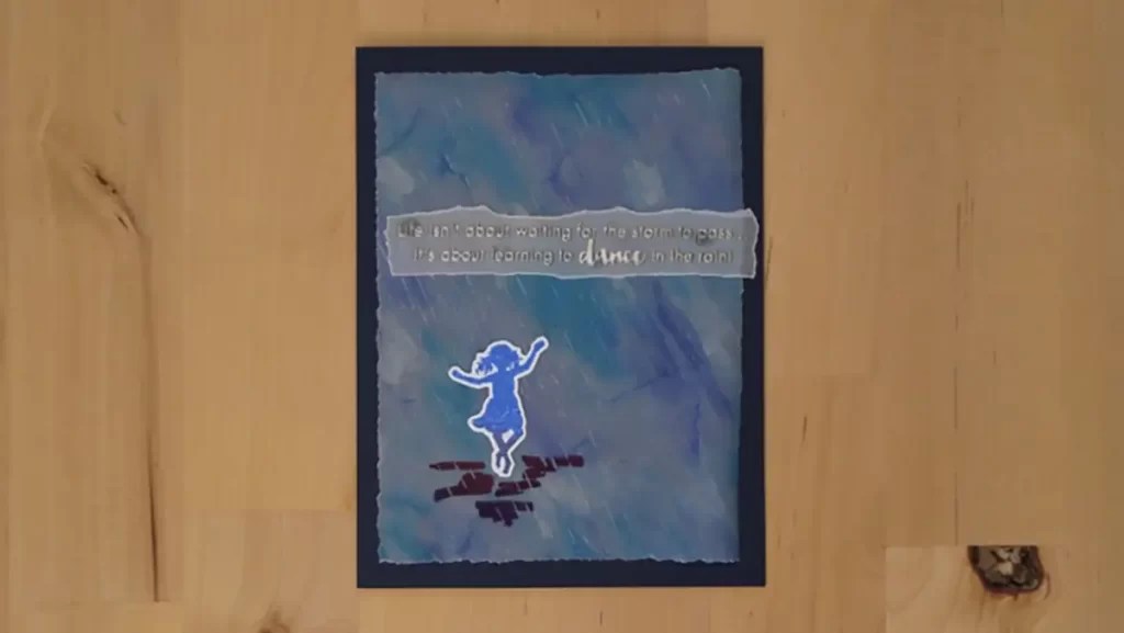 A handmade card with a blue watercolor background, featuring a silhouette of a dancing child and the quote, "Life isn't about waiting for the storm to pass, it's about learning to dance in the rain!"—a true secret card recipe for inspiration.