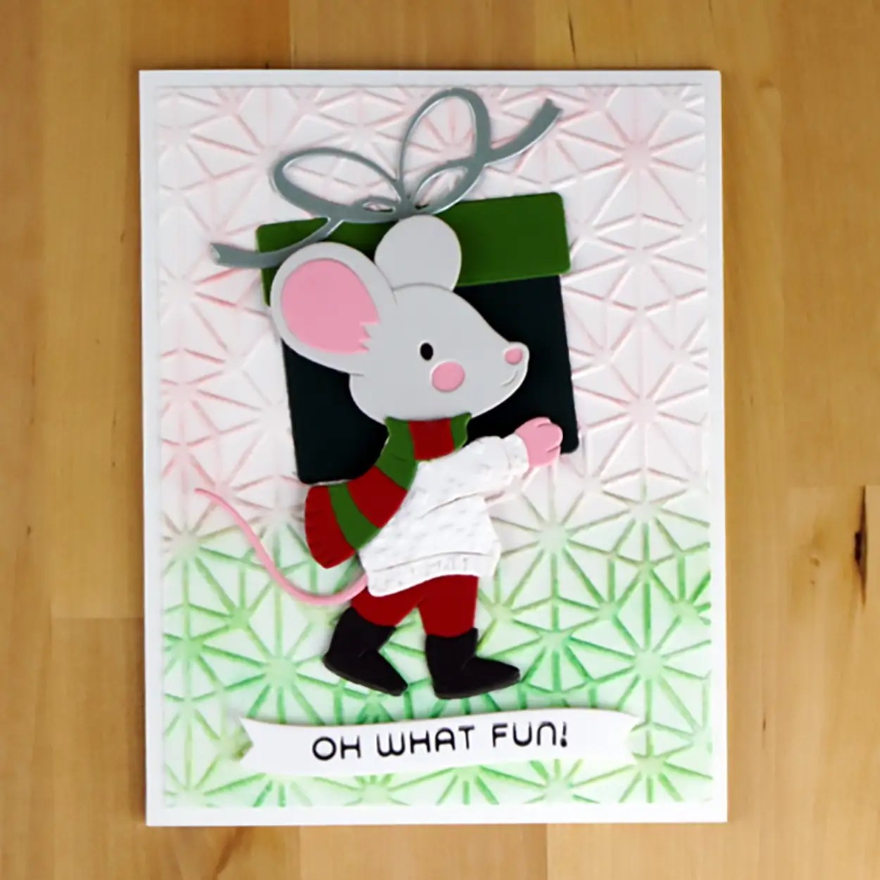 A holiday card featuring a cartoon Giftin' Mouse in a cozy sweater and scarf, carrying a Christmas gift. The card has a textured background and the text "OH WHAT FUN!" at the bottom, perfect to celebrate the festive season.