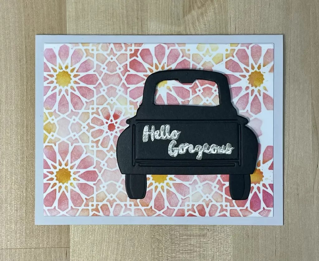 A jaw-dropping card featuring a black car cutout on a colorful geometric floral background. "Hello Gorgeous" is elegantly written in silver across the car, perfect for any cards set collection.