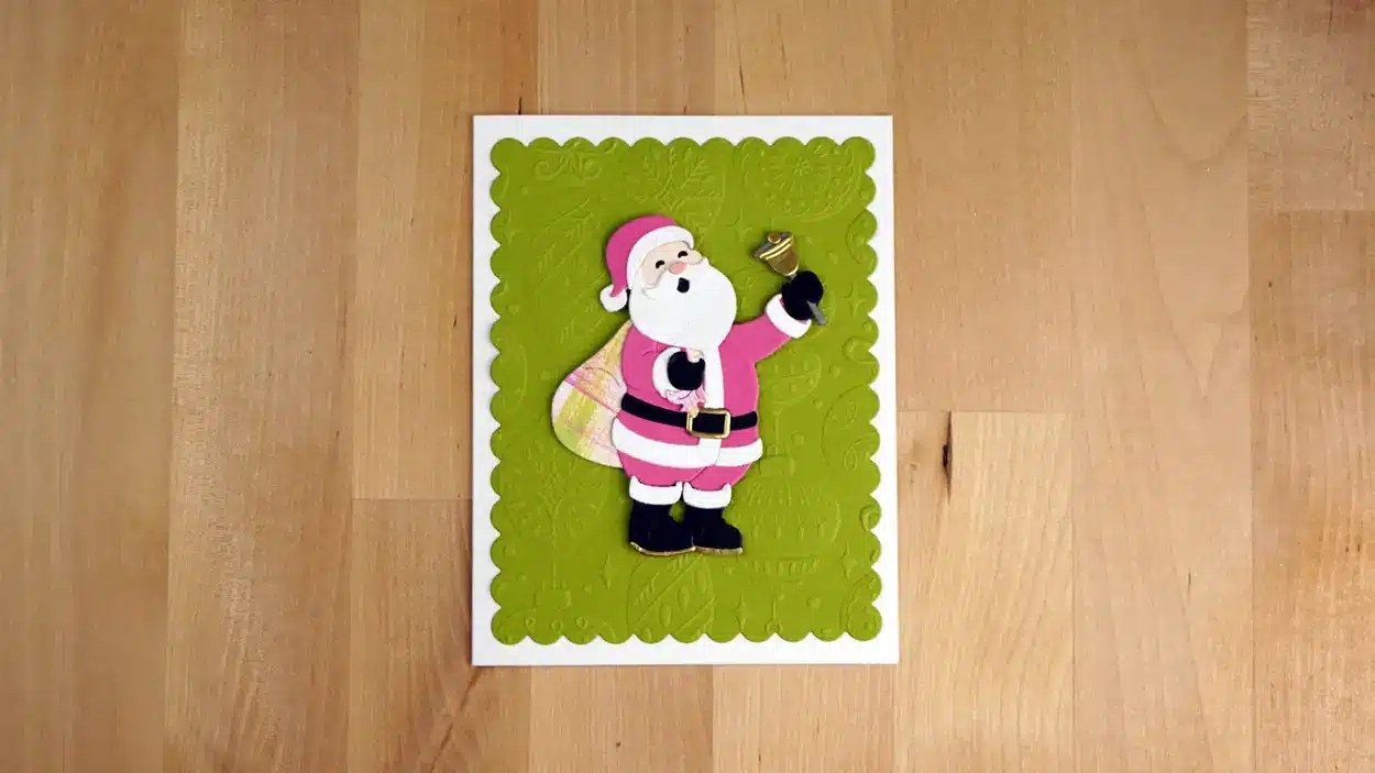 A greeting card with an illustration of Santa Claus in pink attire holding a bell, standing on a green textured background. Perfect for celebrating Christmas In July, this set includes 8 cards to share the festive fun.