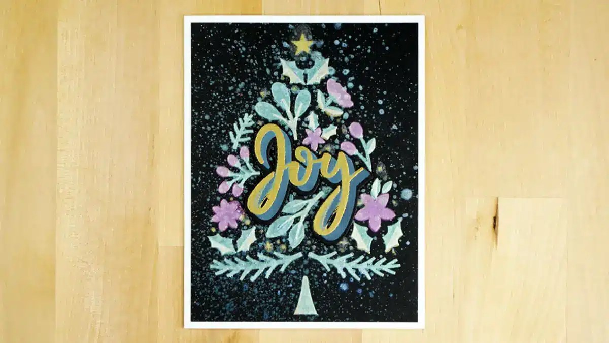 A festive illustration of a Christmas tree with "Joy" written across it, adorned with leaves and flowers. The background is dark, resembling a starry night sky. Perfect for sending out as one of your 8 cards to celebrate Christmas in July.