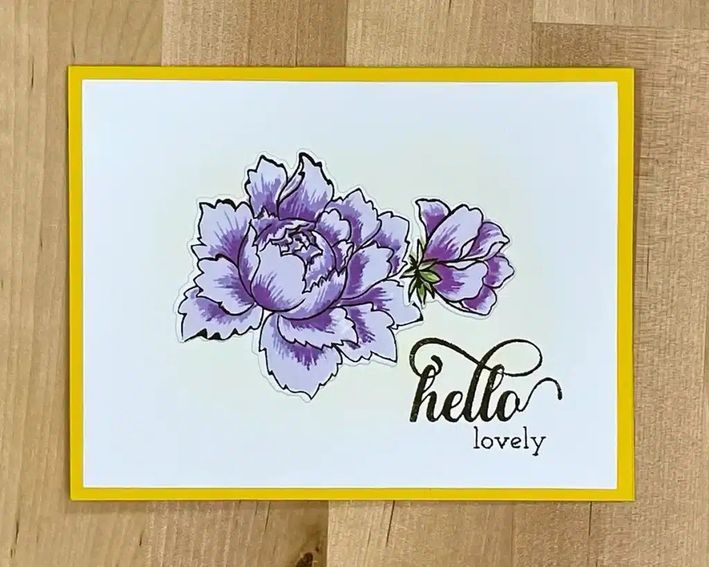 Greeting card with purple flowers and yellow border, featuring the text "hello lovely" in cursive and print, crafted using layered stamping tips for a vibrant, textured effect.