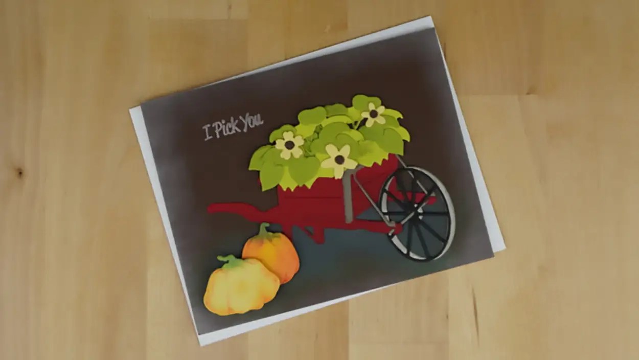 A greeting card featuring an image of a red cart with green plants and two yellow fruits next to it. The text on the card reads "I Pick You." Perfect for those who cherish the charm of country roads.