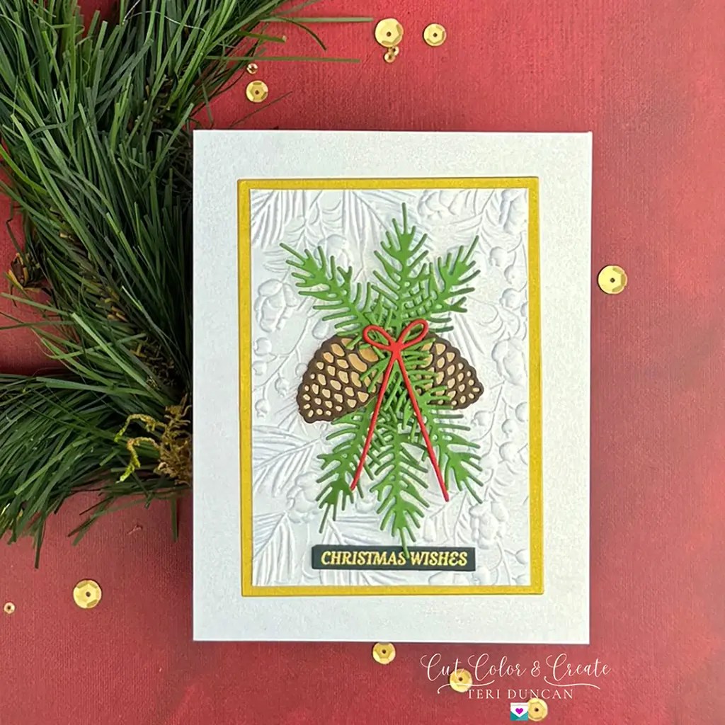 A Christmas card from the Spellbinders Monthly Clubs featuring pine cones and green branches tied with a red bow. The card reads "Christmas Wishes" and is set on a festive red background with scattered gold sequins. Available July 2024.
