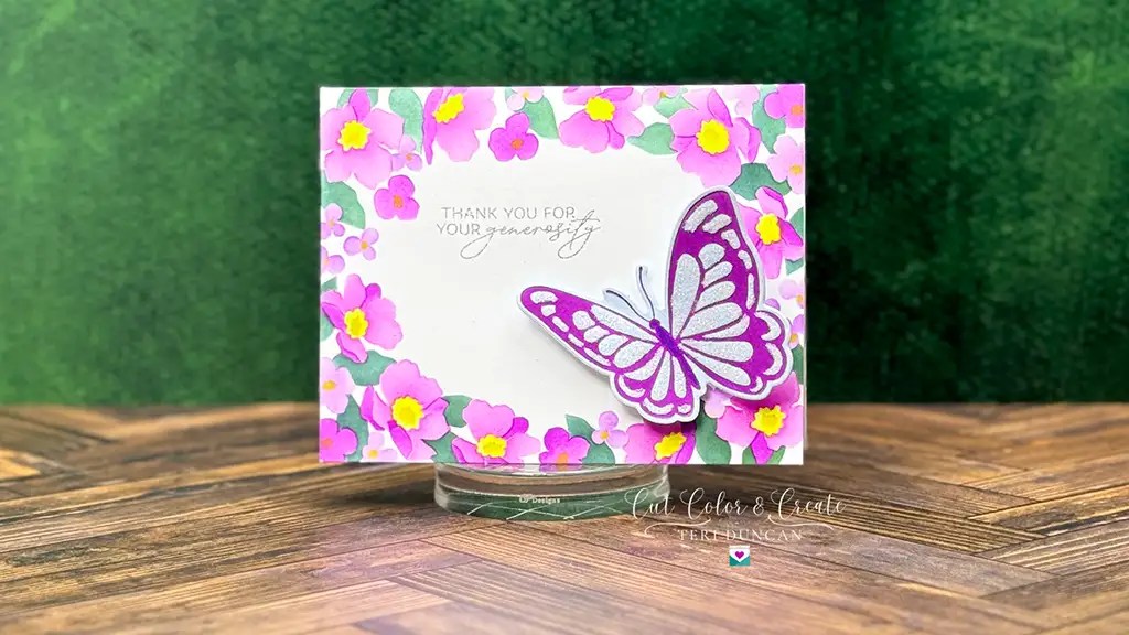 Handmade card crafted with Club Kits, adorned with a butterfly and pink flowers, featuring the text "Thank you for your generosity" on a wooden surface. Created with Stenceil and Betterpress January '25 Club Kits from Spellbinders