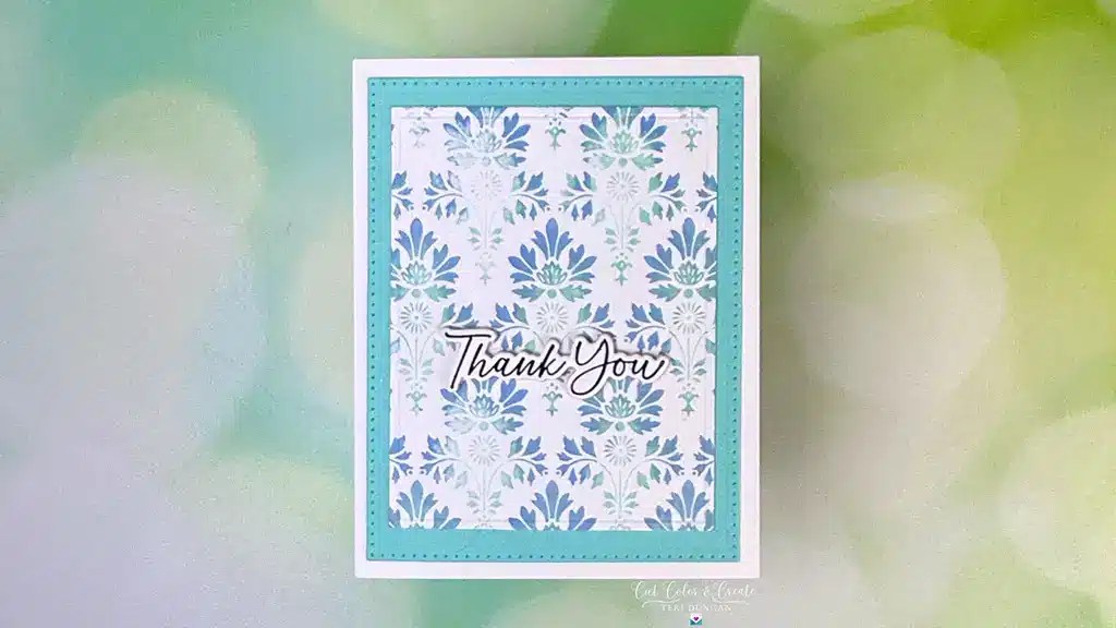 A thank you card from the Spellbinders Spring Release collection, adorned with a floral blue and white pattern. At its heart, "Thank You" is elegantly scripted in cursive text, framed by a delicate blue border.