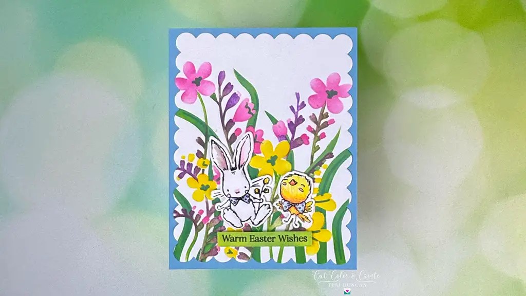 A charming greeting card featuring a rabbit and chick nestled among vibrant flowers. The text reads "Warm Spring Release Wishes," set against a blurred green and white background. Perfect for Spellbinders enthusiasts!.
