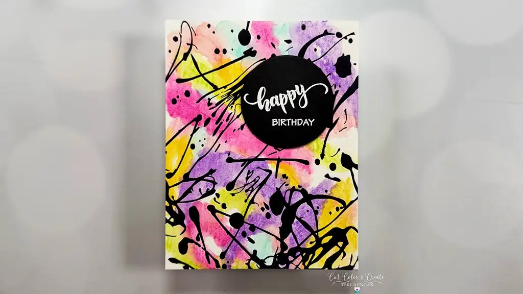 A birthday card with "happy BIRTHDAY" text on a black circle, featuring a colorful abstract background with paint splatters and brush strokes—perfect for cardmaking ideas or to inspire your next take a note card creation.