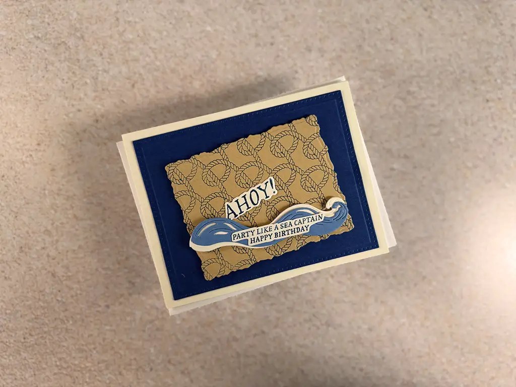 A handmade birthday card from our Nautical Cards Club Kits, featuring "AHOY!" and "Party like a sea captain. Happy Birthday" on a blue and tan background with rope patterns. Make with Spellbinders June '25 club kits