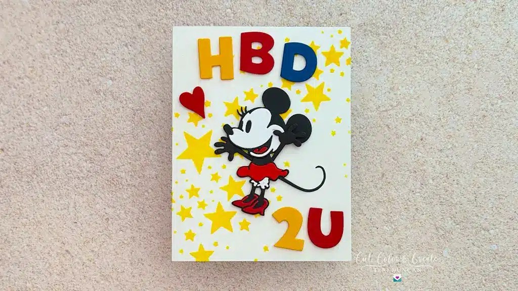 A handmade birthday card from the Darling Mouse Cards collection features a Minnie Mouse cutout, yellow stars, a red heart, and colorful "HBD 2U" letters on a white background.