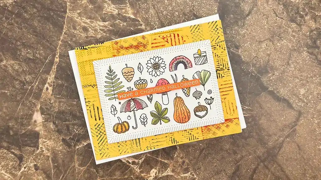A handmade card featuring autumn and Halloween-themed doodles and the text "Have a Charmed Halloween" on a marble surface—perfect inspiration for Autumn card ideas or your Sept 25 club kits.